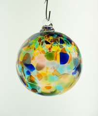 Glass bauble.  Single hand blown glass Christmas tree ornament in clear translucent multicolour on a white background
