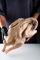 man's hands hold a large fresh turkey for a holiday dinner.