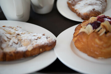 an almond croissant and a bun with strawberry slices lie on a white plate next to a white cup of coffee cappuccino and latte food fresh pastries bakery handmade kitchen cafe breakfast health