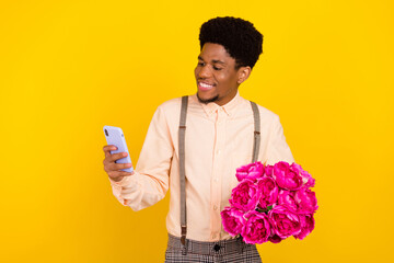 Photo portrait man in shirt keeping flowers bunch on birthday party using smartphone isolated vivid...