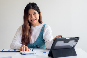 Portrait of Asian young woman working from home , laptop computer and analyzing real estate investment data Financial and tax systems concept.