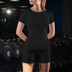 Fototapeta na wymiar Blank compression suit template, black t-shirt, shorts on the girl on the background in the gym.