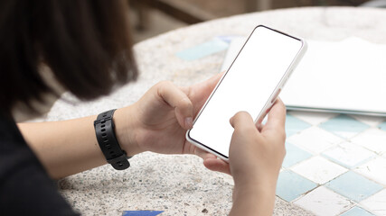 Woman's hands holding or using smartphone with two hands. Smartphone with white blank on screen, Cellphone mockup.