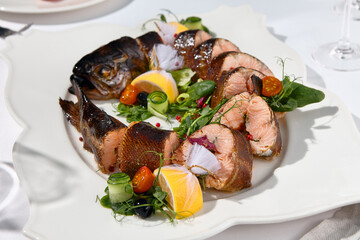 Banquet dishes - smoked rainbow trout on white catering table. Elegant smoked fish trout for dinner party, wedding, holiday party. Food styling for banquet menu.