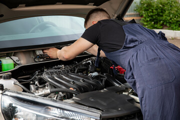 a man repairs a car. a man in blue special clothes to repair the car. engine parts machine repair...