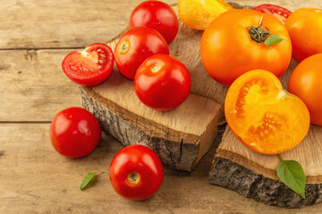 Assorted ripe tomatoes on a wooden stand. Fresh red and orange organic vegetables