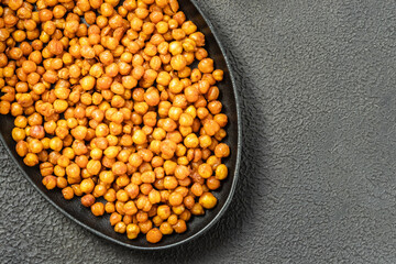 Oven roasted chickpeas in cast iron skillet on dark background. Top view, copy space.
