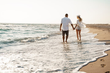 Young beautiful couple walking on beach near sea