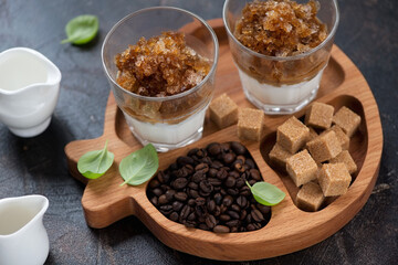 Wooden serving tray with coffee granita in glasses and some of its ingredients, studio shot on a dark-brown stone background