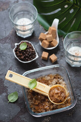 Glass container with coffee granita and a plastic serving spoon over brown stone background, elevated view, vertical shot