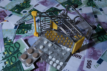 medicines and pills are lying in a small shopping cart against the background of money euro dollars...