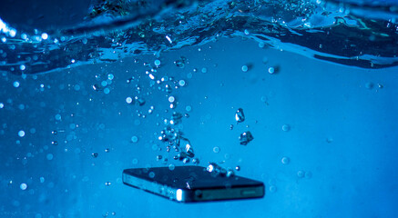 black and white phone dropped into the water. phone in water.phone in water bubbles.phone sinks in...