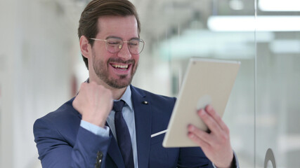 Excited Young Businessman Celebrating Success on Tablet in Office