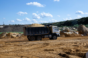 Dump truck transports sand in open pit mine. Excavator on the development of sand in a quarry. Mining industry concept