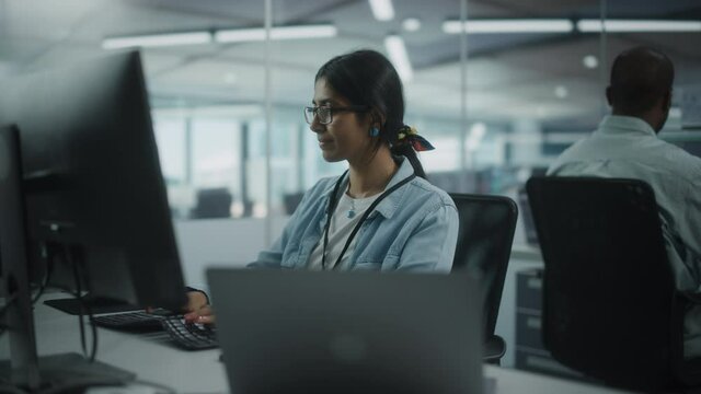 Diverse Office: Portrait of Talented Indian Girl IT Programmer Working on Desktop Computer in Friendly Multi-Ethnic Environment. Female Software Engineer Wearing Glasses Develop Inspirational App