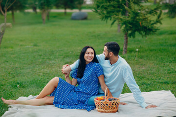 Young adult woman and man couple picnic at green grass meadow in park