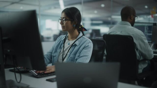 Diverse Office: Portrait of Talented Indian Girl IT Programmer Working on Desktop Computer in Friendly Multi-Ethnic Environment. Female Software Engineer Wearing Glasses Develop Inspirational App