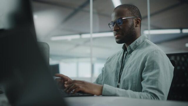 Real Office: Professional Black IT Programmer Working on Desktop Computer. Male Website Developer and Software Engineer Developing App, Video Game. Progressive, Innovative and Inspirational Person