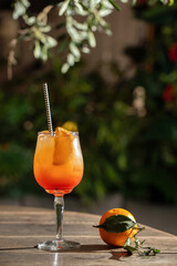 Aperol spritz cocktail with orange and paper straw on wood table