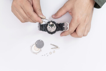 A man use pliers to clamp the digital watch battery remove and change in repairing broken wristwatches on white table