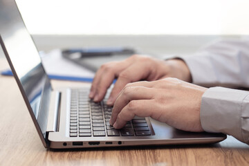 Close up hand a man typing on laptop computer working on wood table work office concept