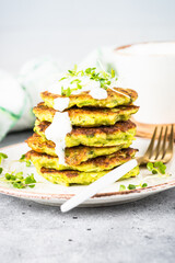 Zucchini pancakes with spinach, hepbs and parmesan cheese, served with sour cream or yogurt. Plant-based eating, alt-meats cutlet.