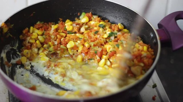 Mixing of egg with corn, carrots in a non stick pan