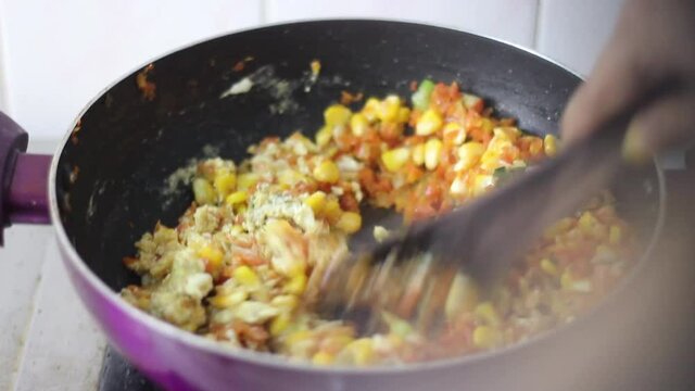 Mixing of egg with corn, carrots in a non stick pan