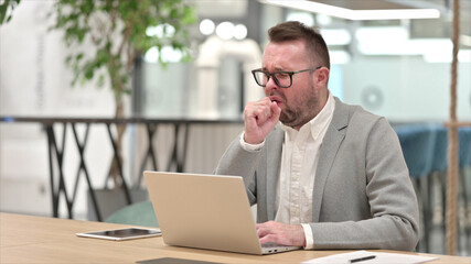 Sick Caucasian Young man with Laptop Coughing in Office