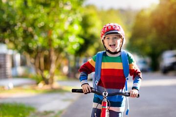 Boy going to school on bike. Kids ride bicycle.