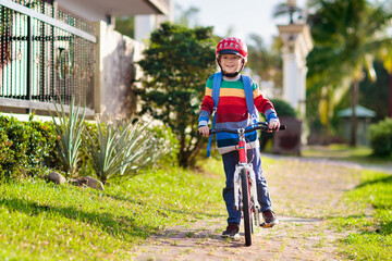 Boy going to school on bike. Kids ride bicycle.
