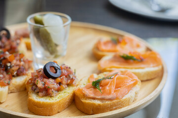 Top view and selective focus of tapas which is small portion appetizer food (smoked salmon, cooked tomato and parma ham on toasted breads) served in european restaurant for sharing before meal.