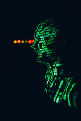 Young man with geen abstract letters on his face in the dark