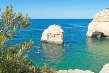Rock formations and people doing kayaks in the Atlantic ocean to visit the Benagil caves seen from above, Algarve, Portugal