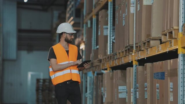 Warehouse manager of a large factory. A manager with a tablet in a warehouse checks the goods