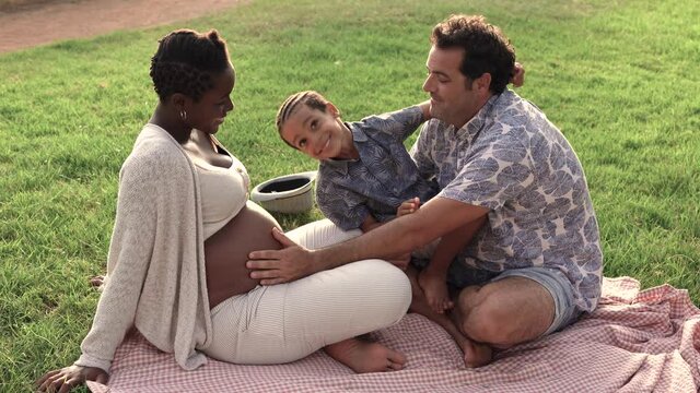 Multiracial family enjoy day at park - Pregnant african mother, caucasian father and mixed race son enjoy day outdoor
