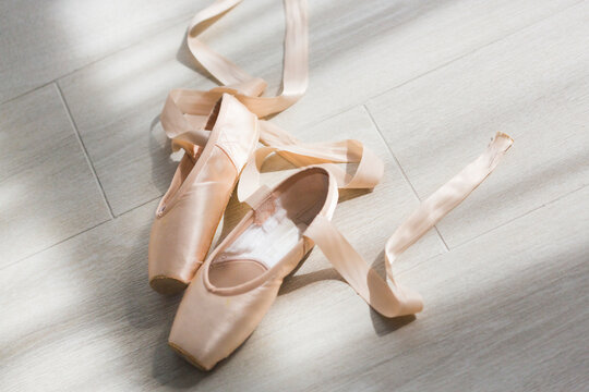 A pair of balerina's pail pink pointe shoes or ballet shoes with ribbons