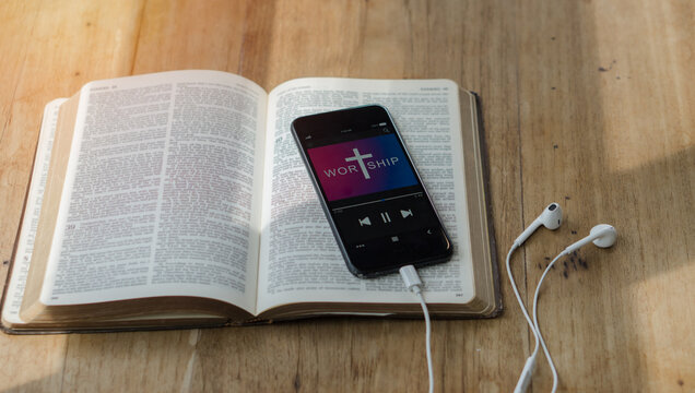 open bible with phone and headphones,Concept listen the words of God.Bible, phone and earphones on wood table, top view.