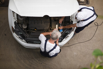Top view shot of car repairment working under the hood of a car at the workshop
