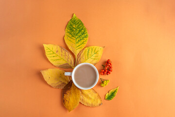 Obraz na płótnie Canvas Autumn composition, layout from yellow dry leaves and cup of coffee on orange background. Minimal, stylish, creative fall still life. Flat lay, copy space
