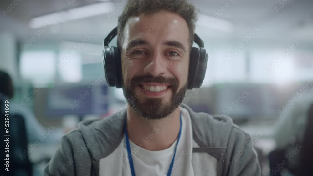Poster Office: Portrait of Happy IT Programmer Wearing Headphones Working on Desktop Computer, Looking at Camera and Smiling. Male Software Engineer Developing App, Video Game. Listening to Podcast, Music