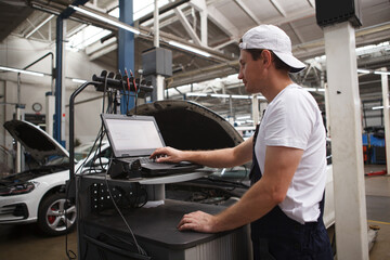 Experienced car mechanic doing computer car diagnostics at the workshop