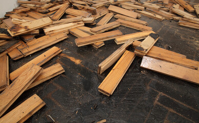 Old damaged parquet removal, heap of small planks at bitumen covered floor