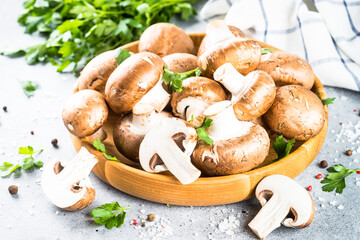 Raw mushrooms Champignon in wooden bowl with spices and herbs for cooking.