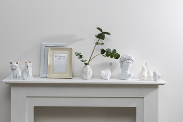 Photo frame with place for text, tceramic figurines of birds, David's head, fox, bear, pears on the side table. Corrugated vase with a branch of dried eucalyptus. Office decoration. Copy space