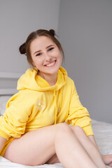 happy positive brunette in yellow hoodie in bright room. happy people. millennial generation. fashionable teenager. trendy colours