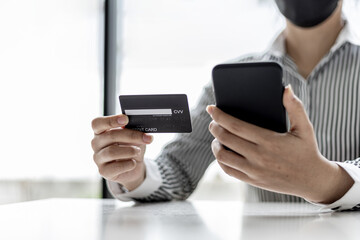 Woman holding a smartphone and a credit card, she is filling out her credit card information to pay for the purchases made through the smartphone app. Online shopping and credit card payment concept.