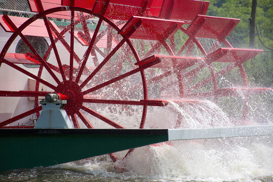 close up of red paddlewheel boat on a river with water spray 