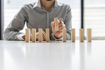A woman is holding wooden blocks in a row, she grabs the center piece to complete them, the wooden...