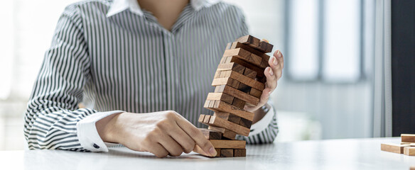 A businesswoman is supporting a wooden block that is working so it doesn't fall down, like running...